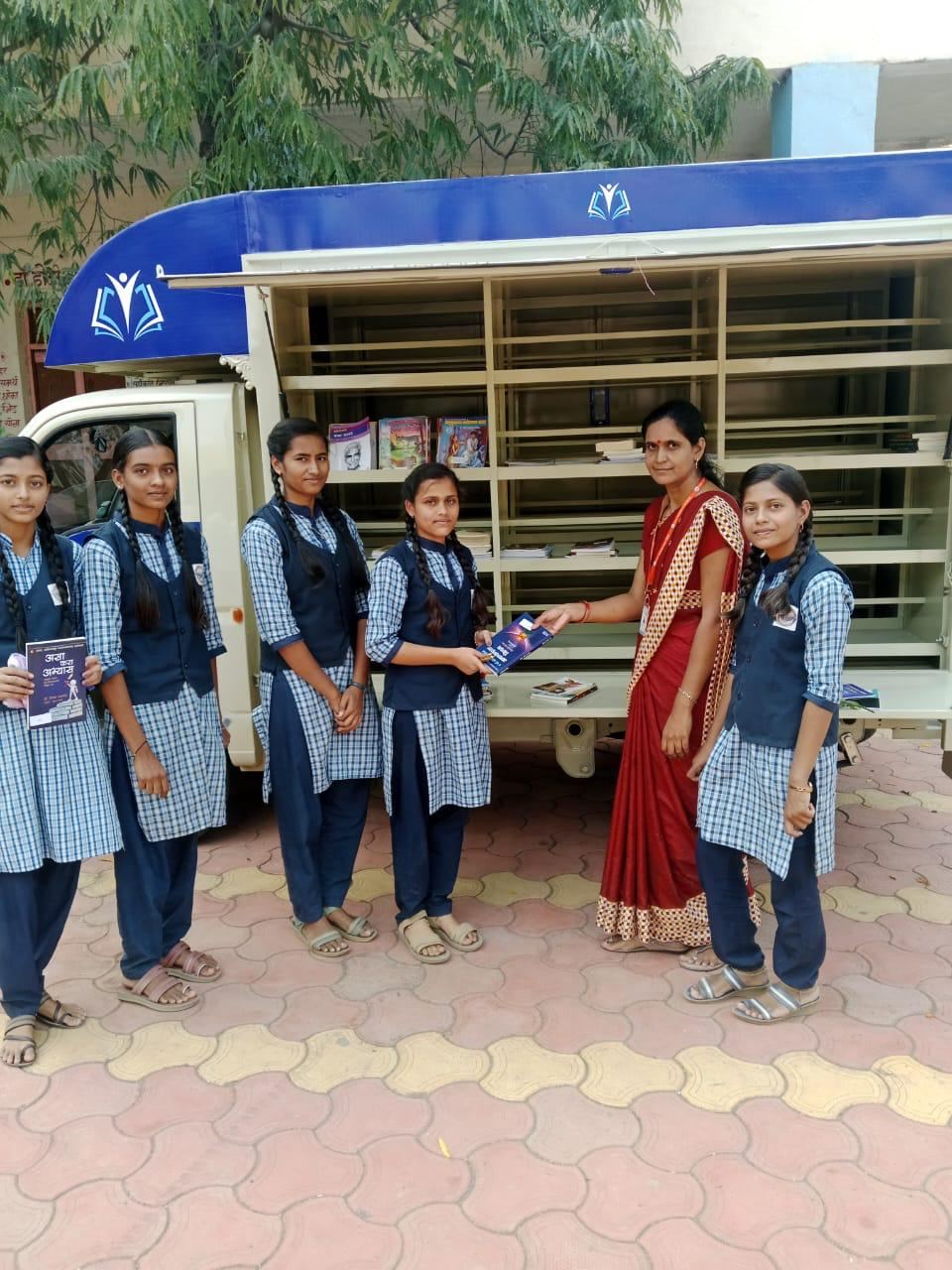 Students choosing books from the shelves of a Palavi mobile library van